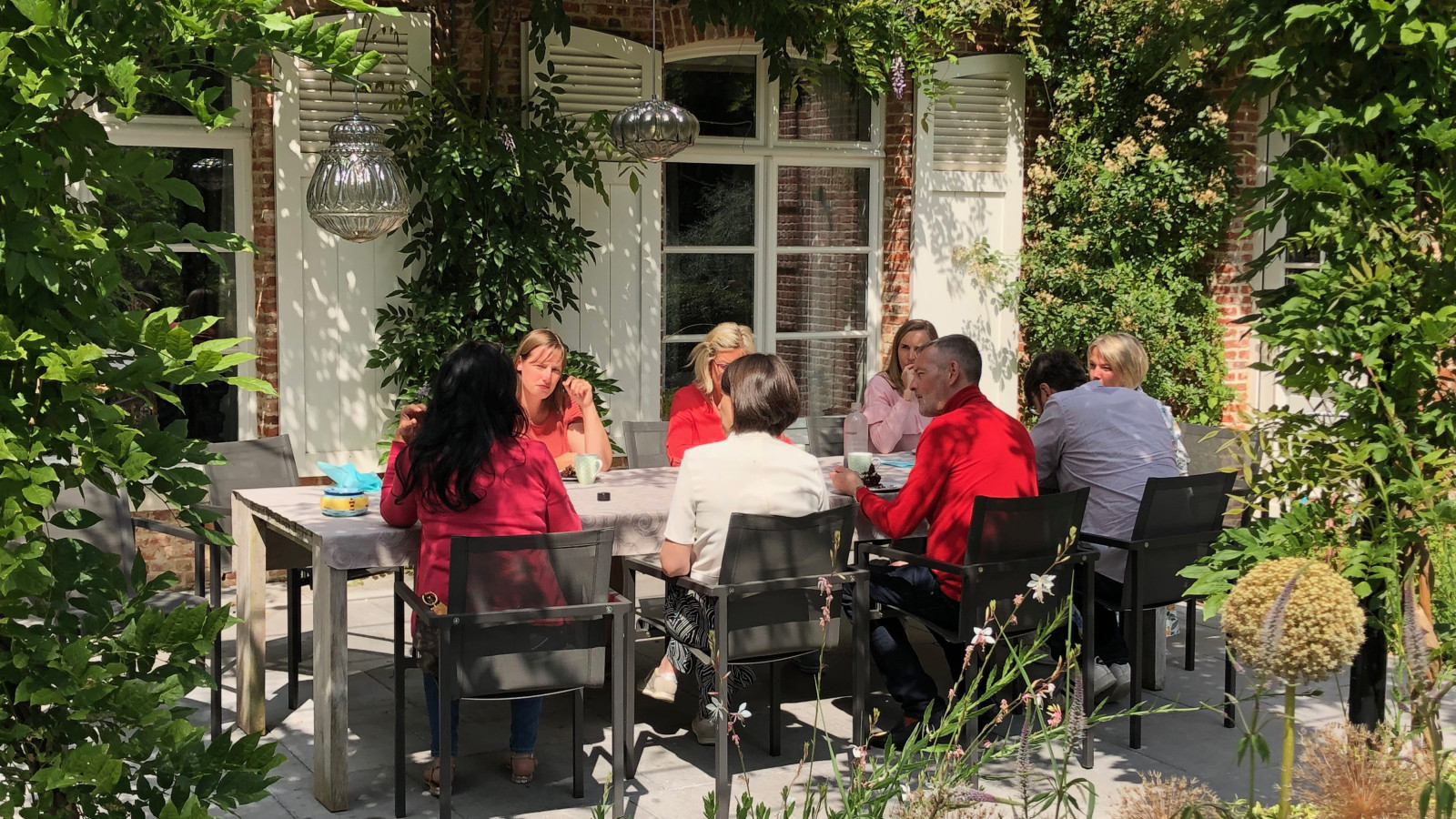 Groep mensen in gesprek aan een tafel buiten